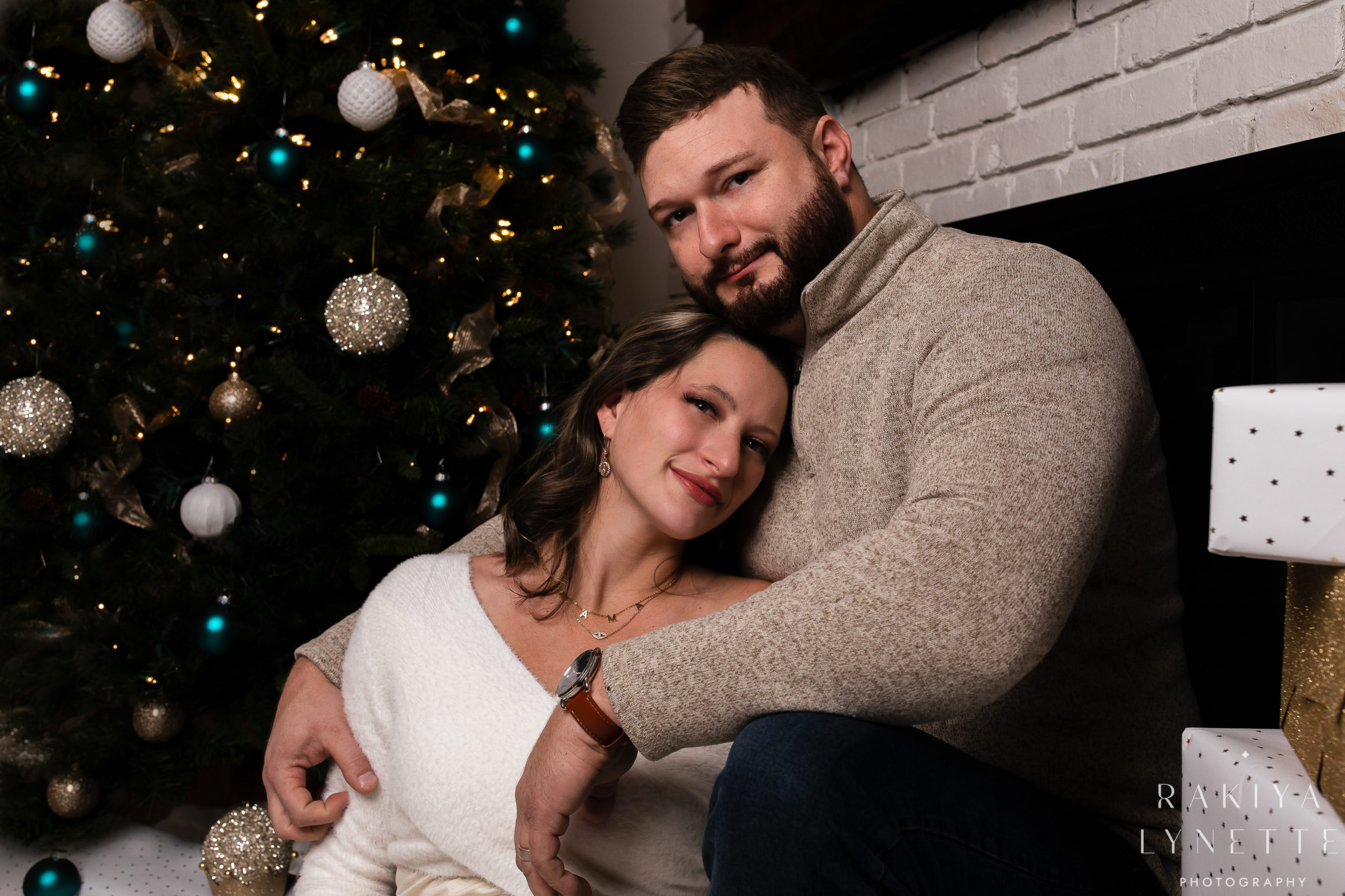 wife leaning her head on husbands chest in front of a christmas tree in new york